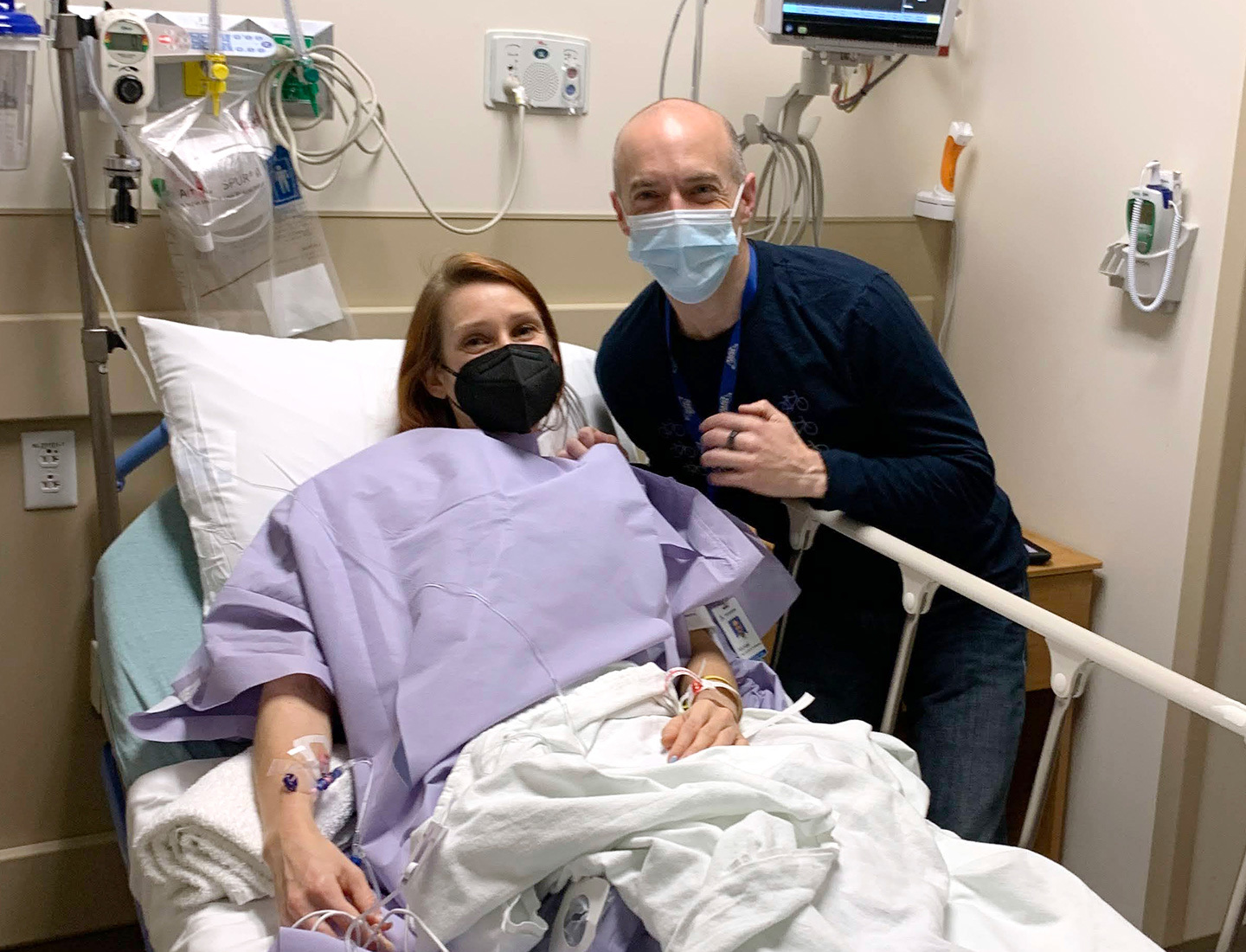 Victoria Threadgould's husband leans over her hospital bed and smiles alongside her in preop.