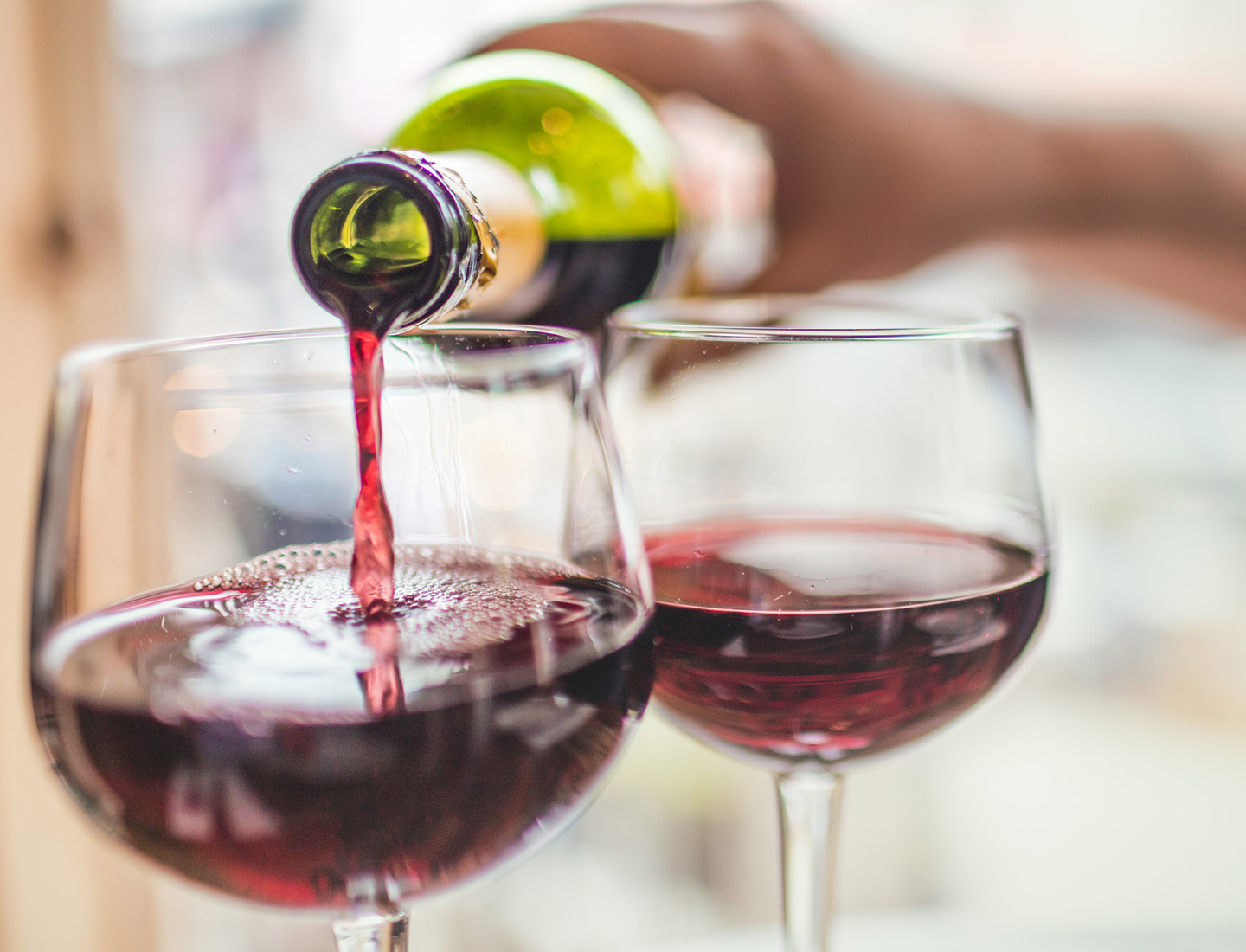 Close-up of wine being poured into one glass next to a glass that has already been filled.