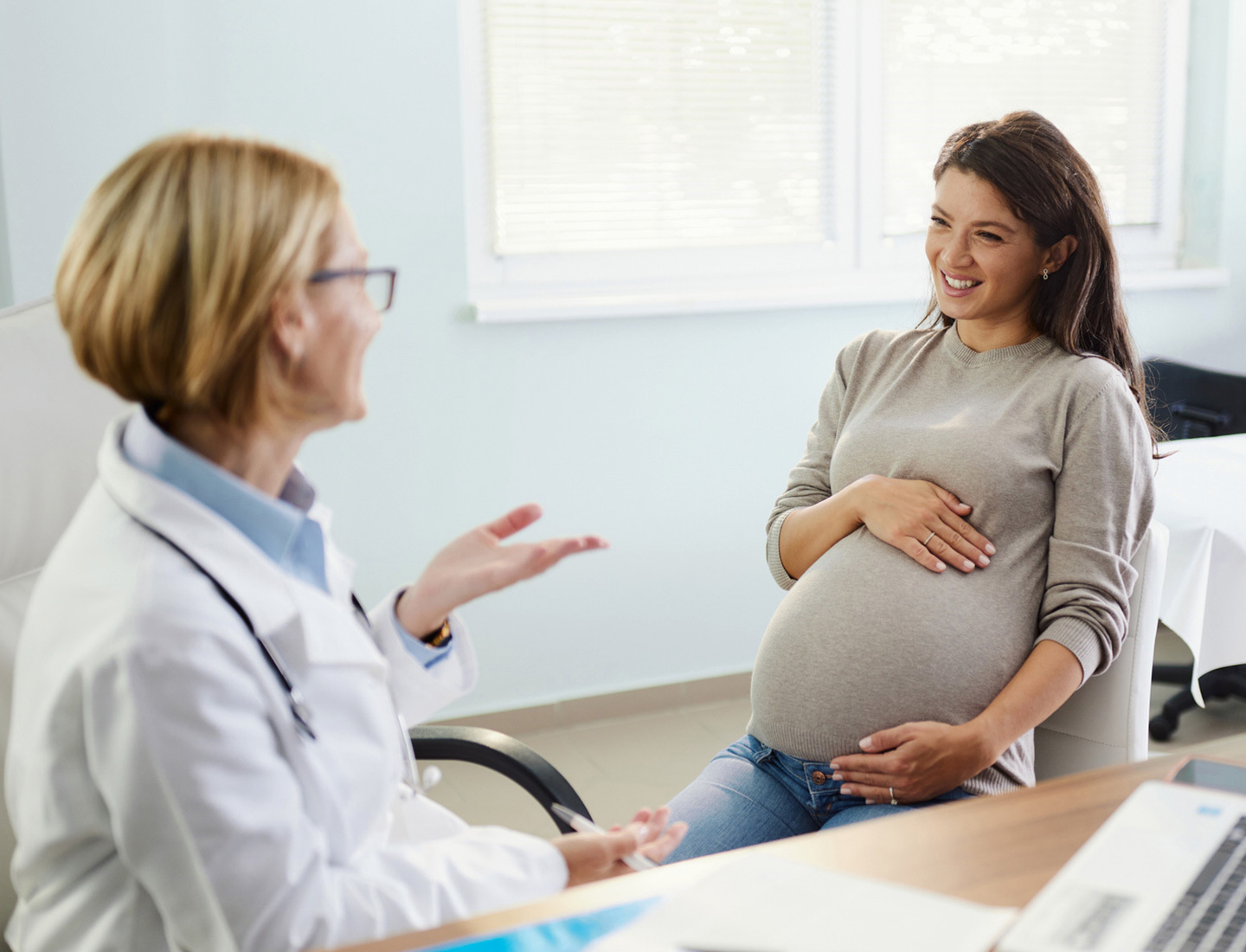 A pregnant woman speaking to a doctor at an appointment.