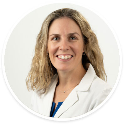 Headshot of Dr. Eileen Stewart smiling in a white coat with wavy blonde hair.