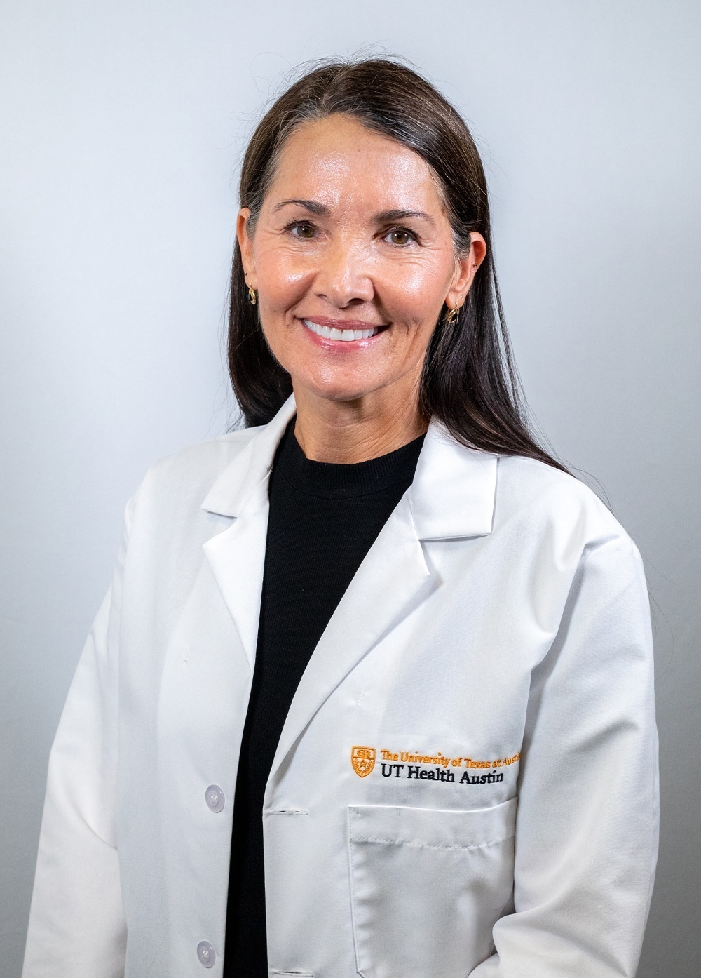 Psychologist Janie Black, PhD, wearing a white coat and smiling in front of a white backdrop.