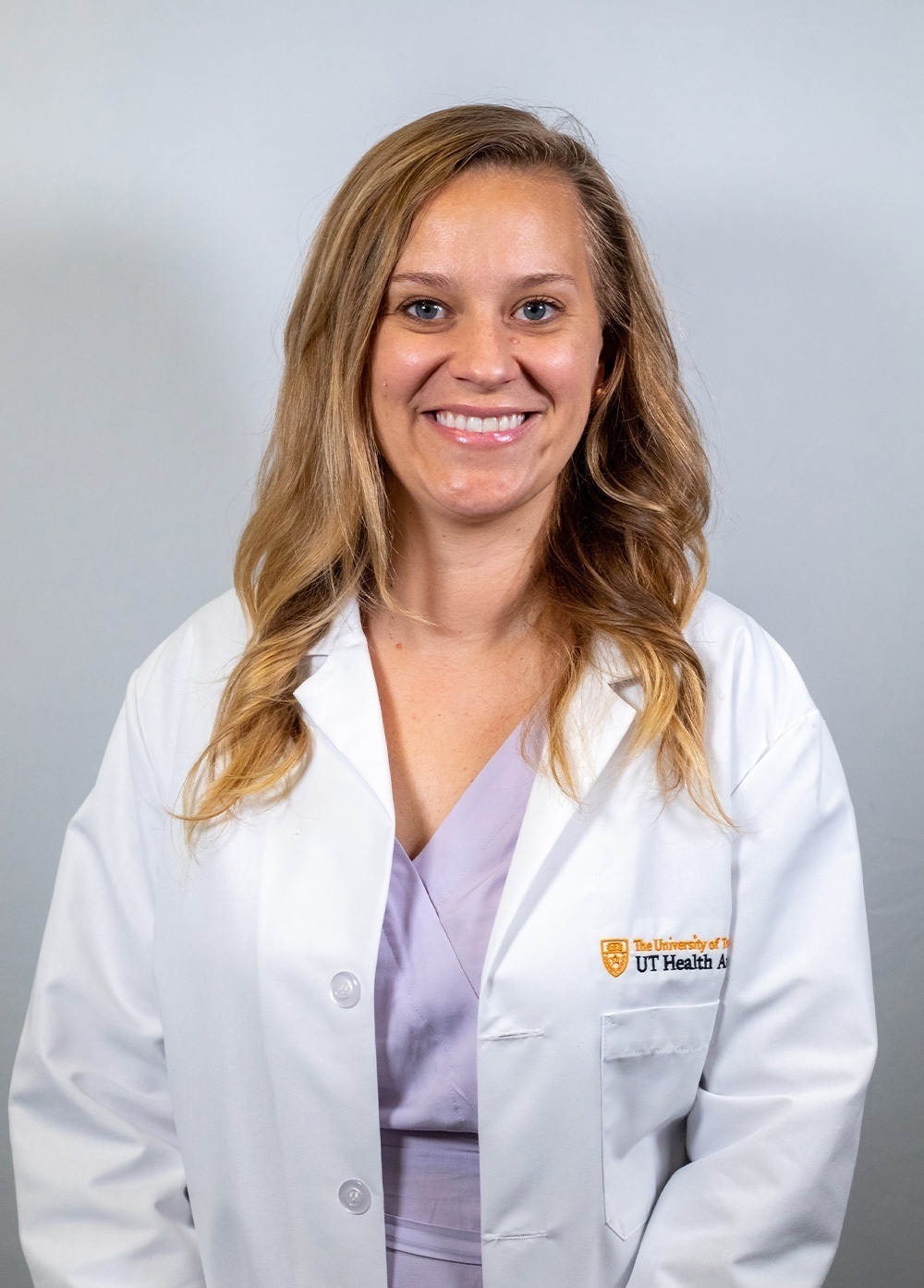 Pediatric psychologist Meredith Brinster, PhD, wearing a white coat and smiling in front of a white backdrop.
