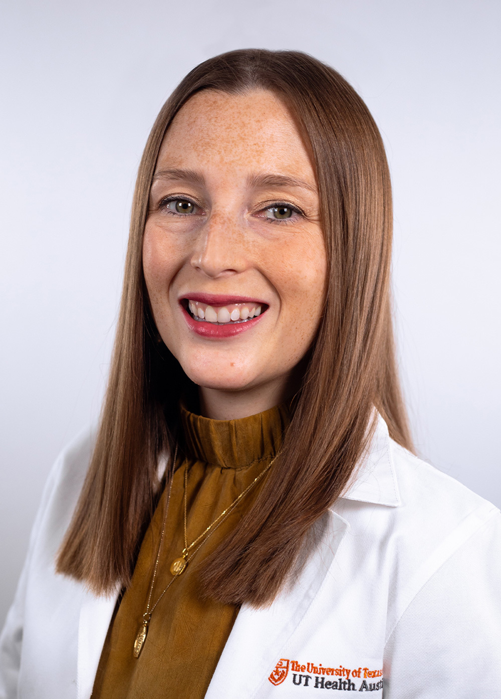 Pediatric nurse practitioner Olivia P. Martino, MSN, BS, APRN, CPNP-PC, wearing a white coat and smiling in front of a white backdrop.
