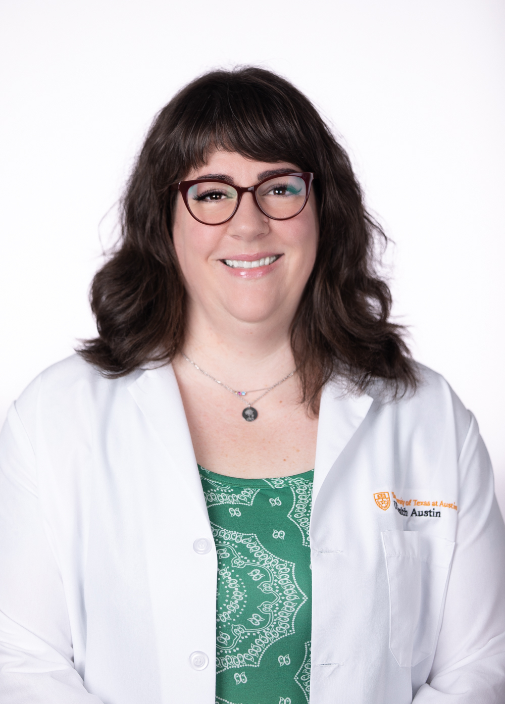 Allison Behr wearing a white coat and smiling in front of a white backdrop.