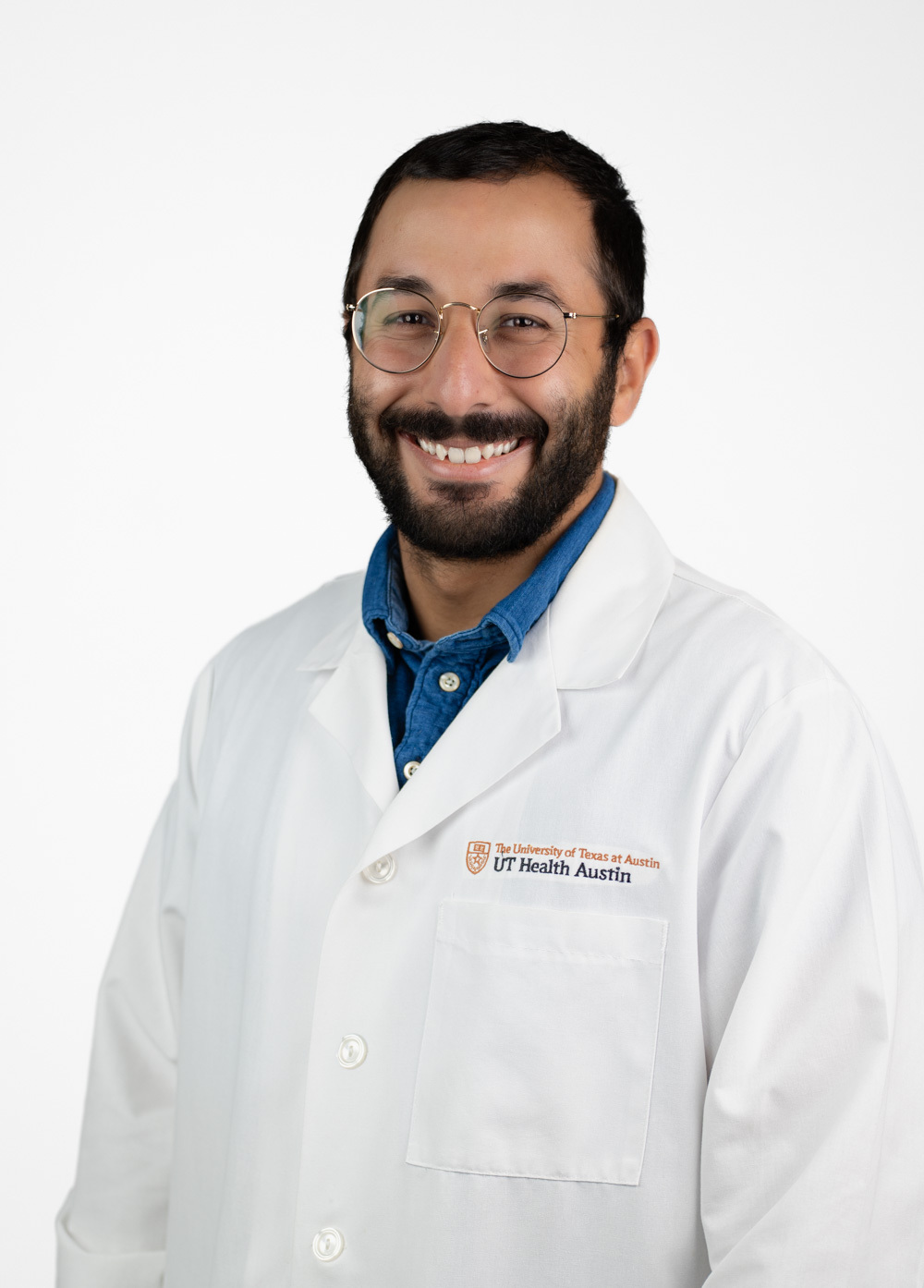 Dr. El-Bokl is smiling and looking at the camera. He is wearing a white coat and a blue dress shirt.