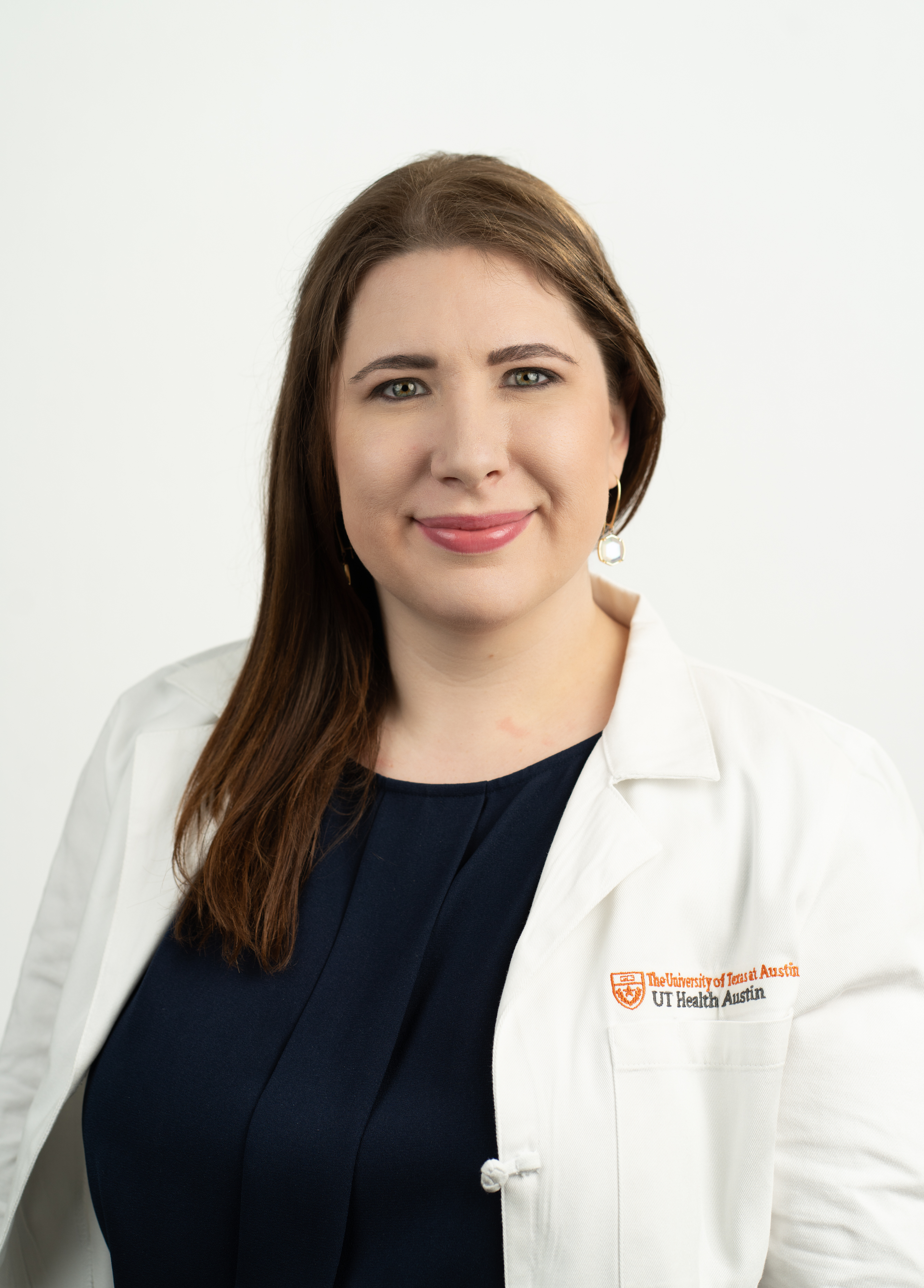 Chelsey Ortman, MD stands in front of a white background smiling into the camera