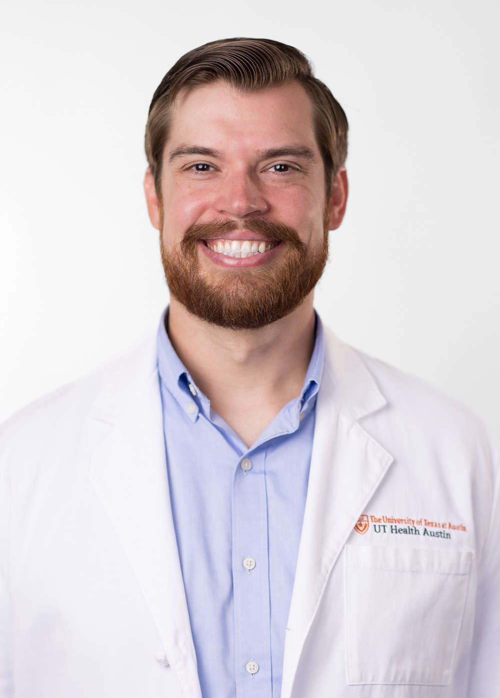 Dr. David Dalton is smiling at the camera. He is wearing a white coat and a light blue dress shirt.