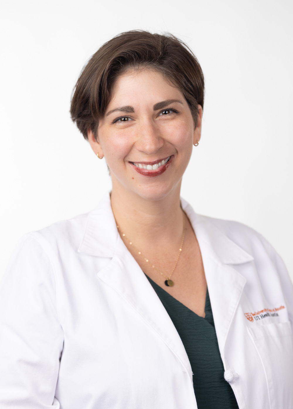 Dr. Elizabeth Rosenthal is smiling and looking at the camera. She is wearing a white coat and a dark green blouse.
