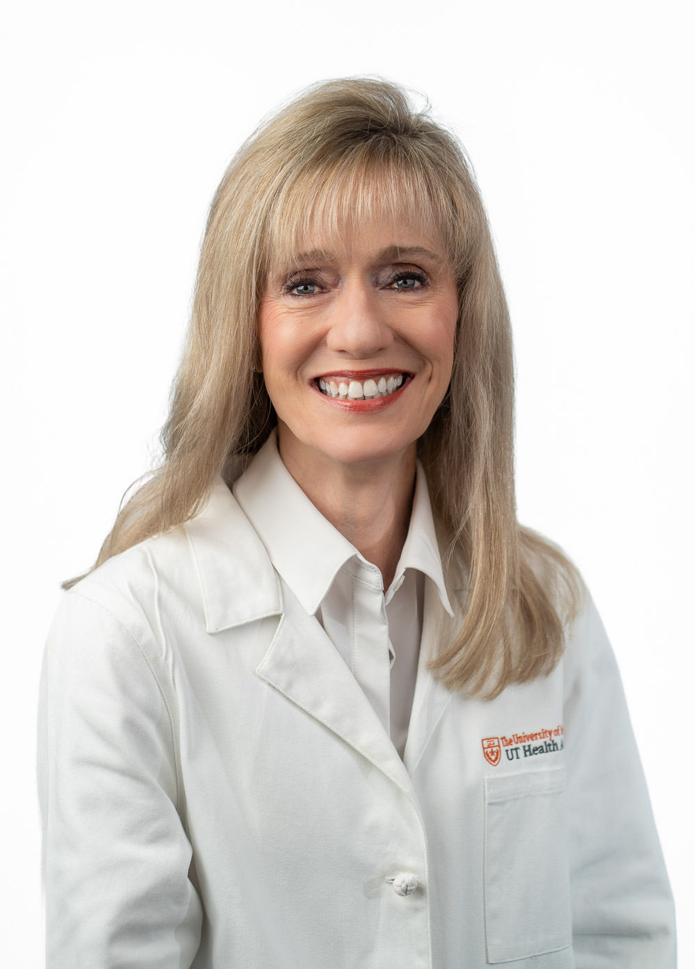 Karen Evankovich is smiling at the camera. She is wearing a white collared shirt under a white coat.