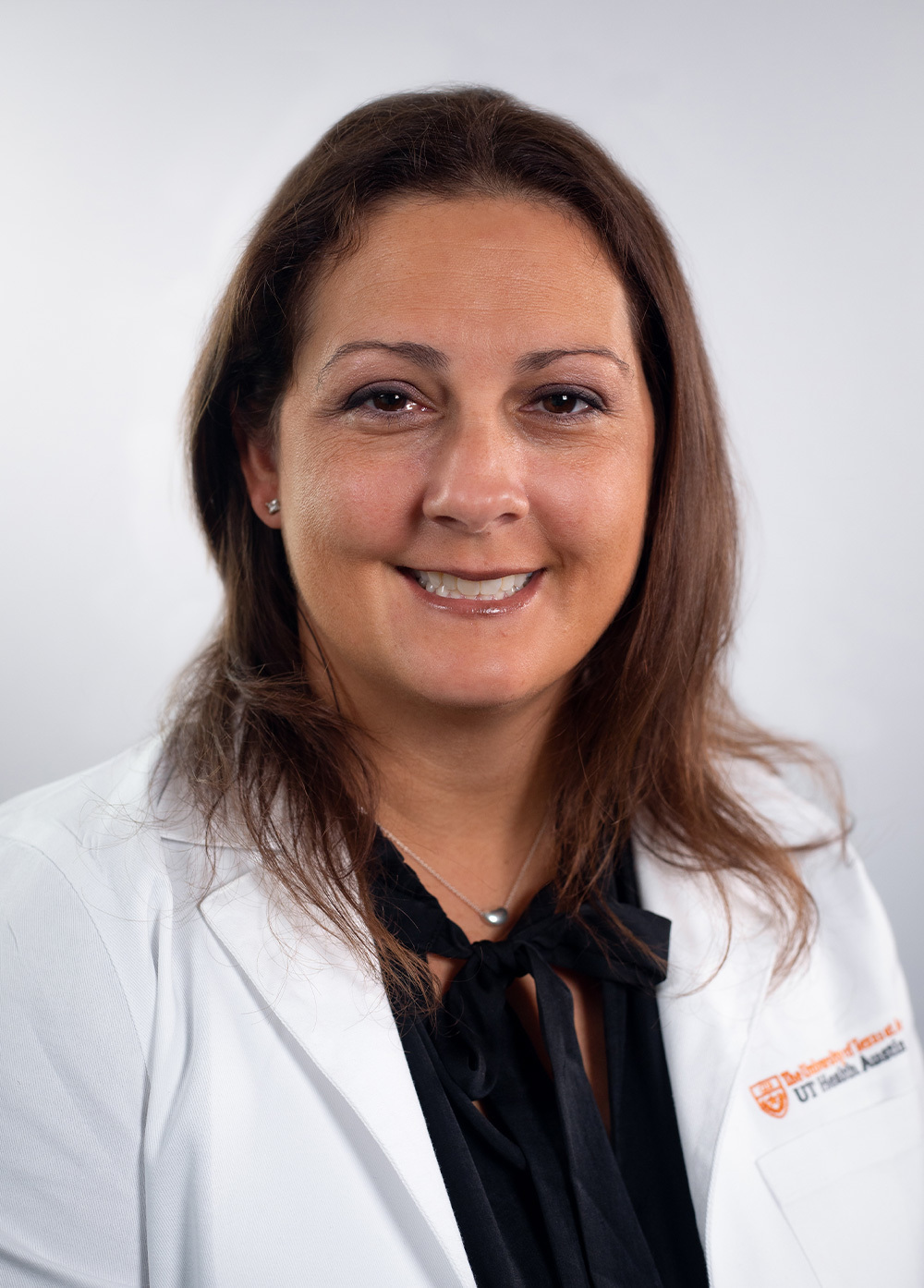 Pediatric nurse practitioner Jamie Fitzgerald, CPNP-PC, wearing a white coat and smiling in front of a white backdrop.