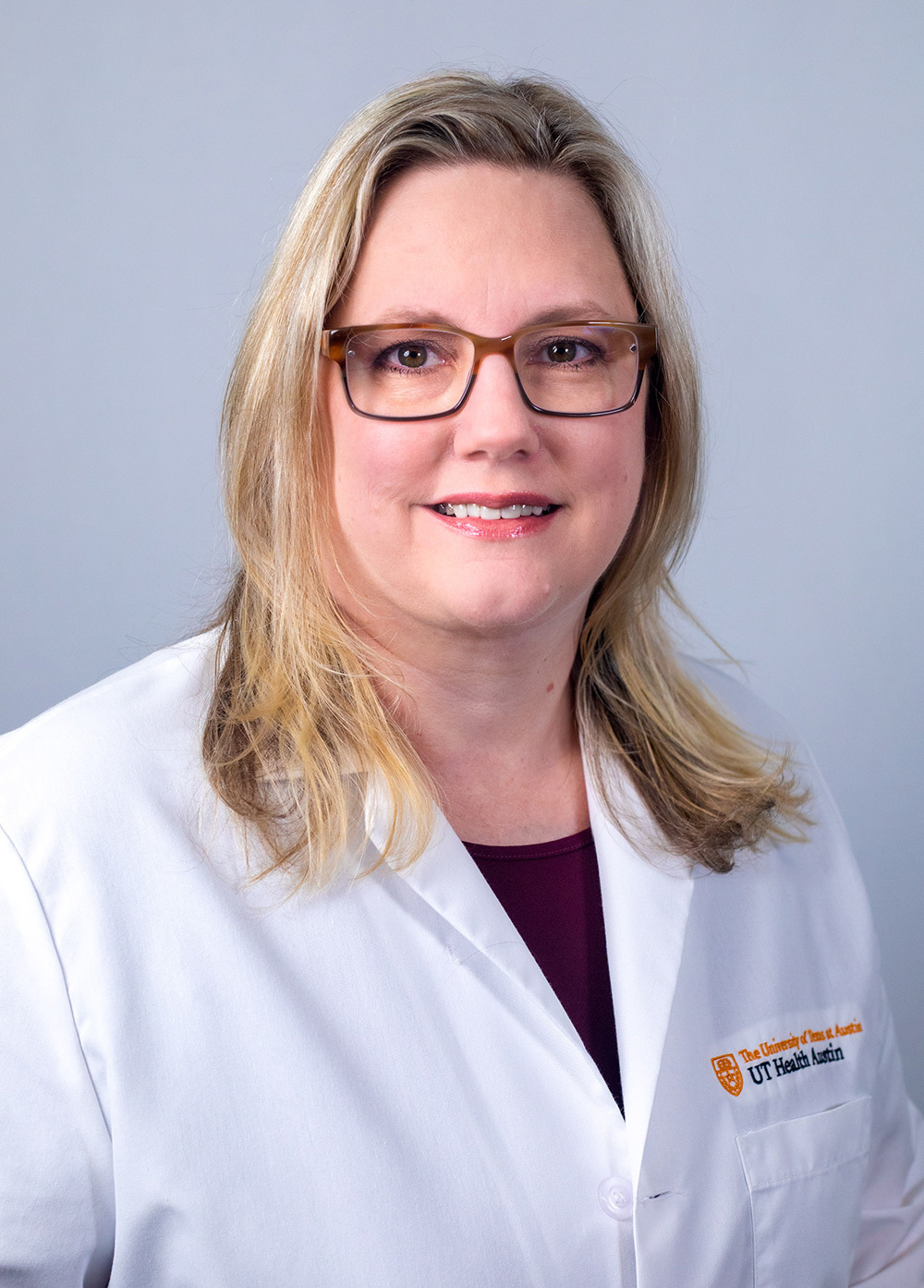 Family nurse practitioner Jena Hiltenbrand, MSN, FNP-C, wearing a white coat and smiling in front of a white backdrop.