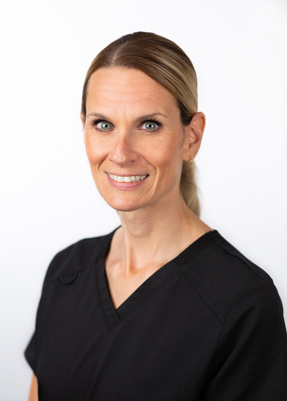 Acute care pediatric nurse practitioner Joy Vanderway, DNP, MBA-HA, CPNP-AC, wearing dark scrubs and smiling in front of a white backdrop.