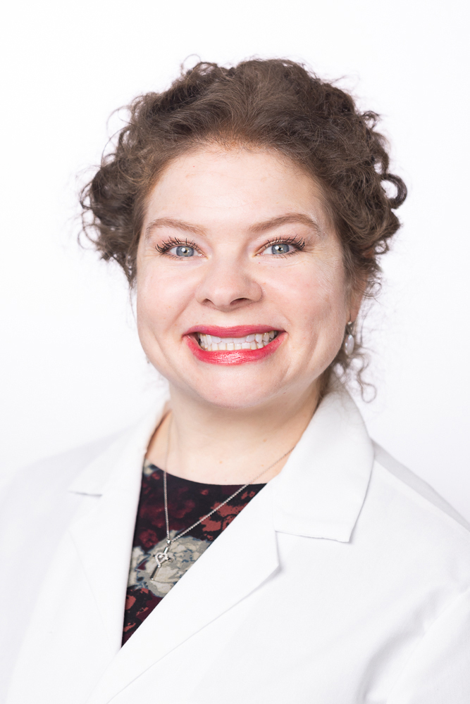 Family nurse practitioner Kimberly Garrett, MSN, APRN, FNP-C, IBCLC, wearing a white coat and smiling in front of a white backdrop.