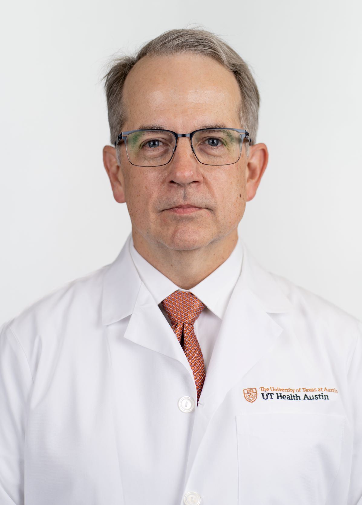 Dr. Michael Taylor wearing a white coat and smiling in front of a white backdrop.