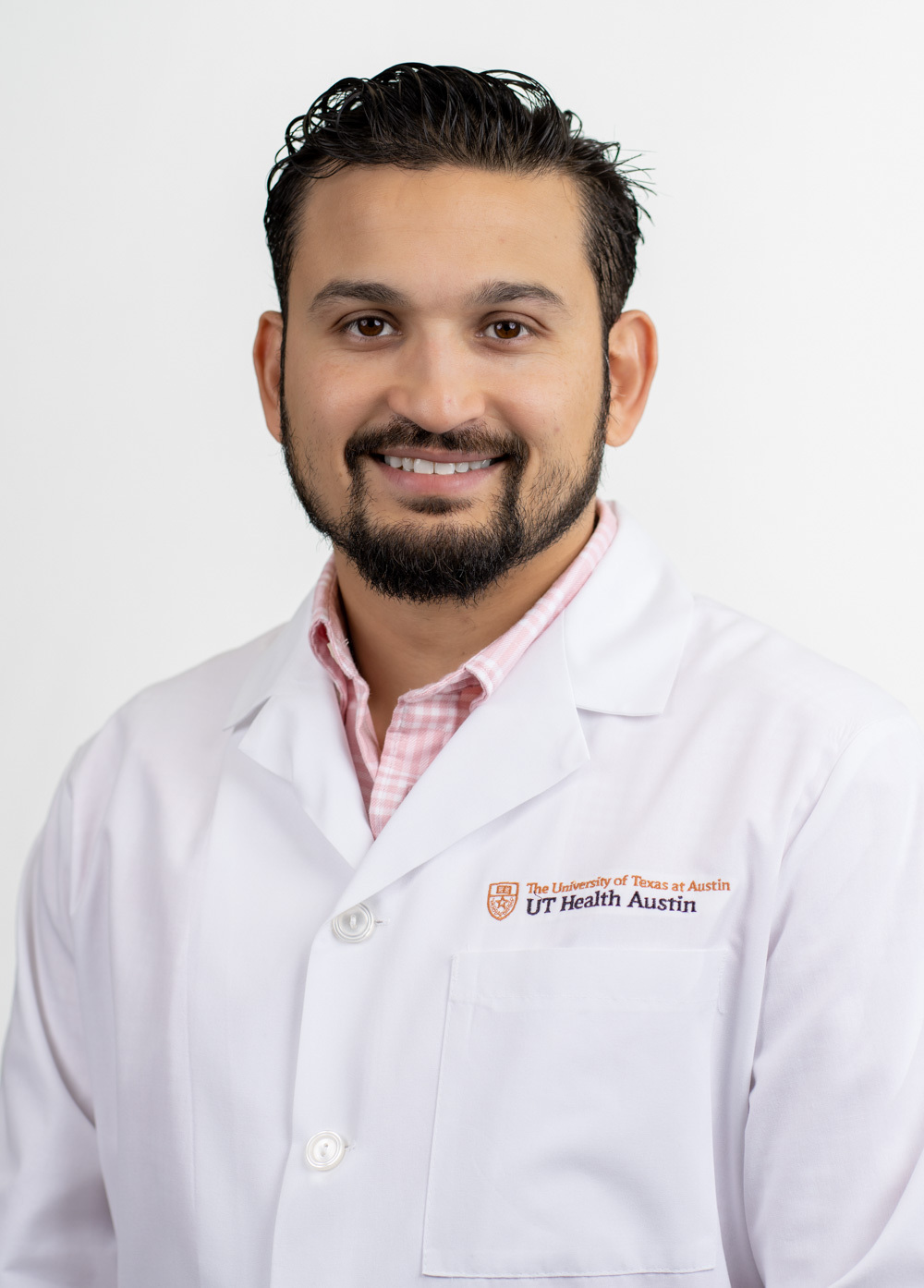 Dr. Omar Iqbal wearing a white coat and smiling in front of a white backdrop.