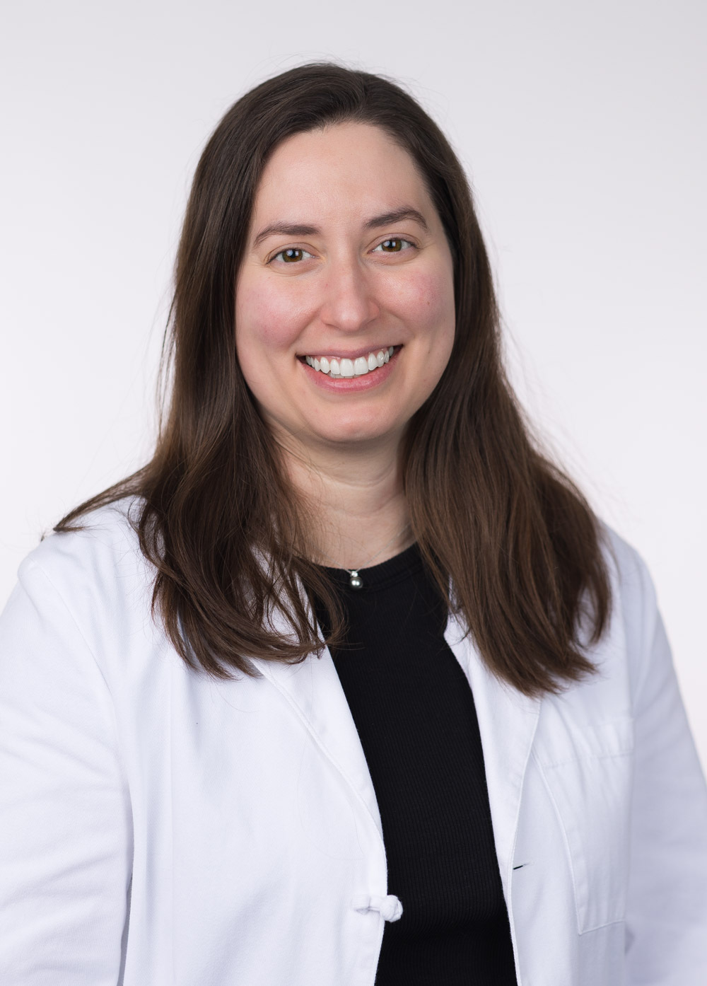 Headshot of Dr. Rachel Mis. She is wearing a black blouse and a white coat.