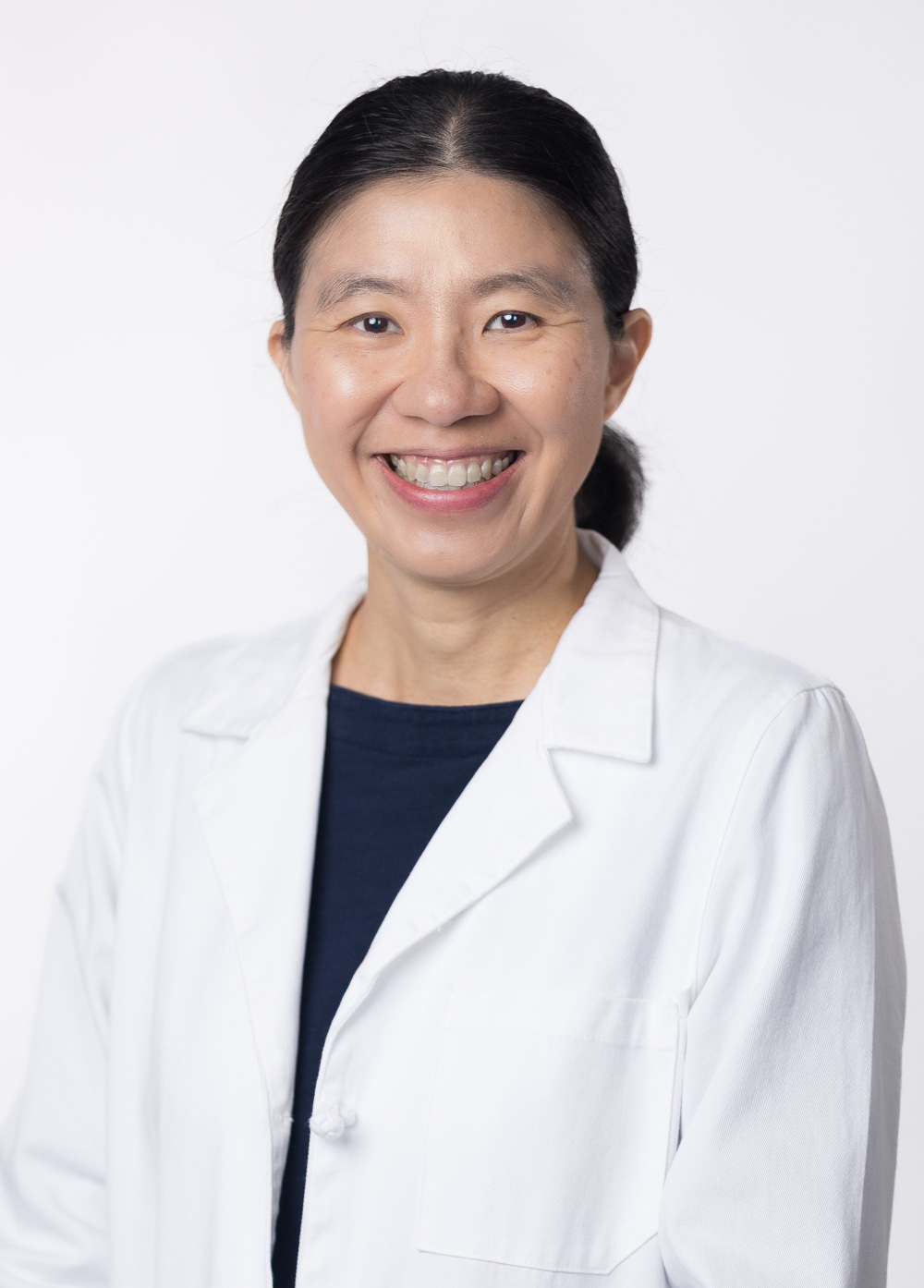 Dr. Ting-Yi Chen is smiling at the camera against a white backdrop. She is wearing a dark navy blue blouse and a white coat.